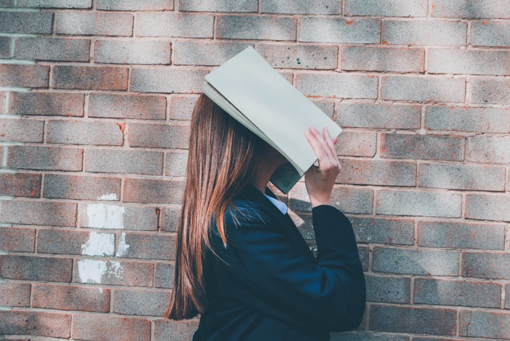 woman covering her face with a book